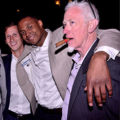 Groom, father and grooms friends outside wedding reception smoking cigars