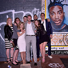 Friends posing in front of a wall of graffiti with the bride and groom